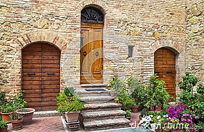 Pienza, Italy â€“ July 22, 2017: Three wooden front doors in the home. Typical doors on a stone wall in the Tuscany town Pienza. Editorial Stock Photo